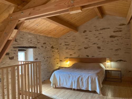een slaapkamer met een bed in een stenen muur bij Gîte Le COCON au Clarou in Valleraugue