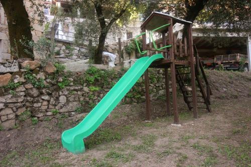 a green slide in a yard next to a building at Casa dos Meões by Gerês Casas in Geres