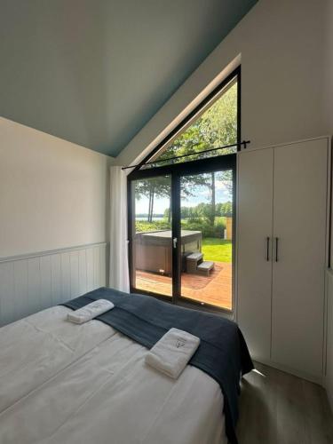 a bedroom with a bed and a large window at Lakeview Houses in Gil Mały
