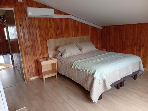 a bedroom with a bed and a wooden wall at Loft Central in Coihaique
