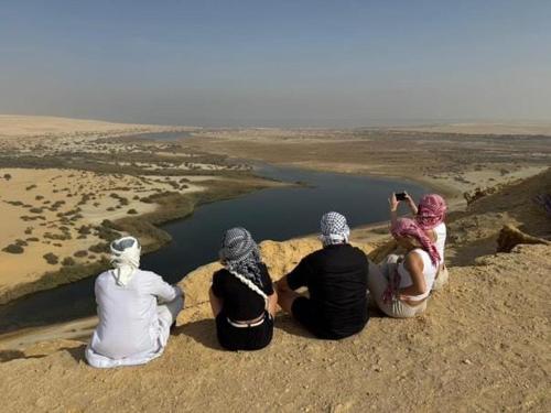 een groep mensen zit op een rots en kijkt naar een rivier bij Fekry House wady rayan in Kafr ‘Amr