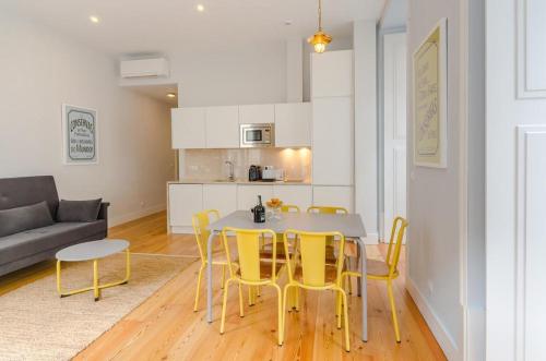 a living room with a table and yellow chairs at Residencial Neves - Baixa in Lisbon