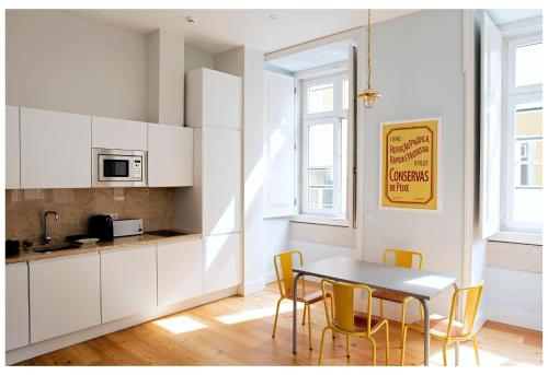 eine Küche mit weißen Schränken und einem Tisch und Stühlen in der Unterkunft Residencial Neves - Baixa in Lissabon