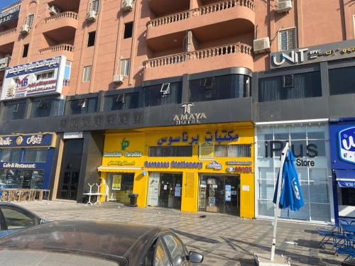 ein großes Gebäude mit einer gelben Ladenfront in einer Straße in der Unterkunft فندق تمايا العاشر من رمضان in Madinat Al Ashir min Ramadan