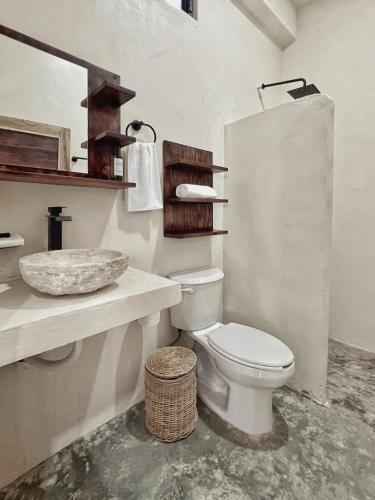 a white bathroom with a toilet and a sink at Hotel Lydna Ki'n in Bacalar