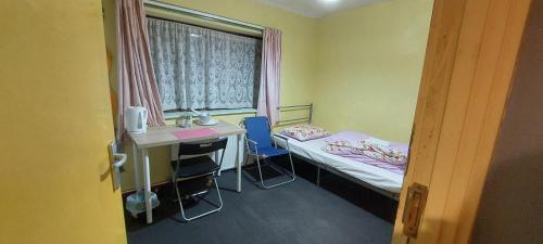 een kamer met een bed, een bureau en een raam bij Basildon House of Muralist in Basildon