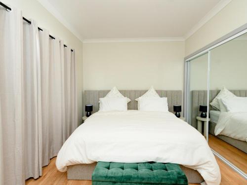 una camera da letto con un grande letto bianco con un pouf verde di Hunter Valley Modern 4-Bedroom House a North Rothbury