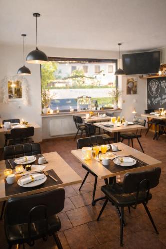 un restaurant avec des tables et des chaises en bois et une grande fenêtre dans l'établissement Pension zur Quelle, à Deudesfeld