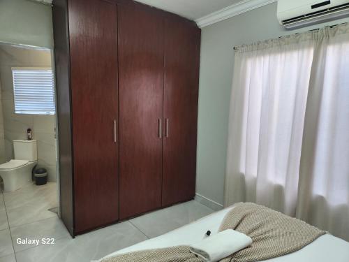 een badkamer met een grote houten kast en een badkuip bij Pado B & B in Gqeberha