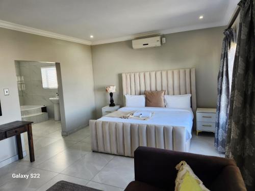 een slaapkamer met een groot wit bed en een bank bij Pado B & B in Gqeberha