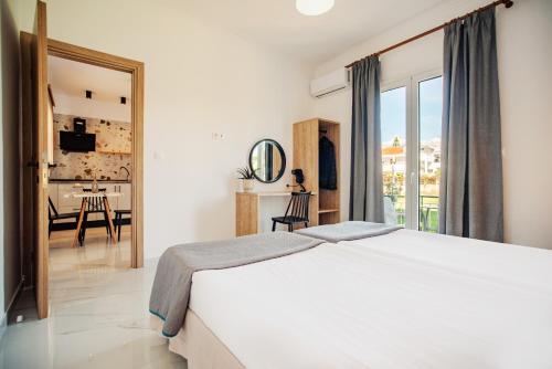 a bedroom with a white bed and a view of a kitchen at Kokkinia Gardens in Kavos