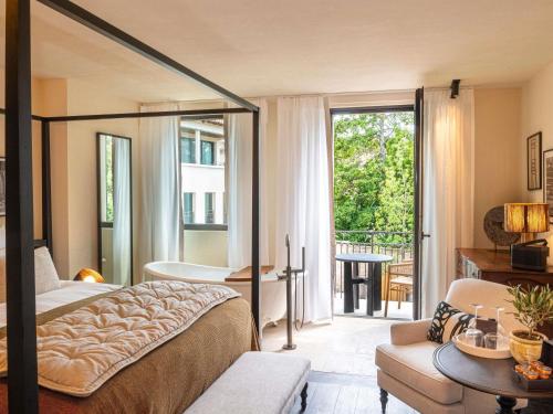 a bedroom with a bed and a balcony with a tub at L'Isle de Leos Hotel & Spa - MGallery Collection in LʼIsle-sur-la-Sorgue