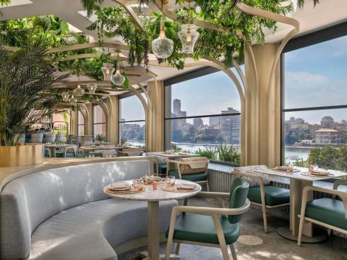 a restaurant with tables and chairs and large windows at Sofitel Cairo Downtown Nile in Cairo