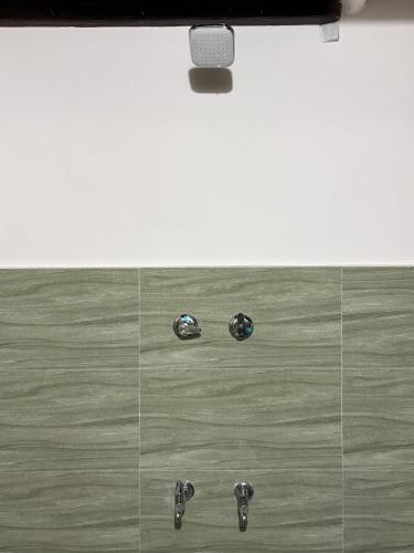 a shower with two knobs on a glass wall at Ekantham Heritage Homestay in Tiruchirappalli