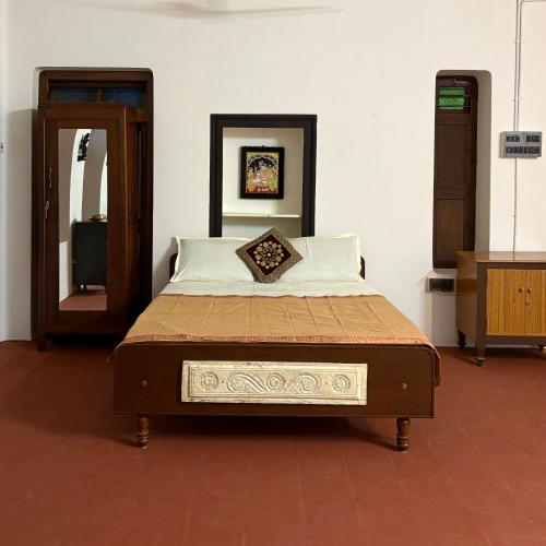 a bed sitting in a room with a mirror at Ekantham Heritage Homestay in Tiruchirappalli
