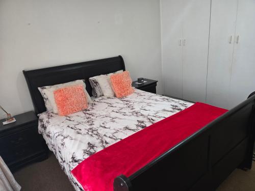a bedroom with a bed with a red blanket on it at Hillcrest Cosy Cottage in Hillcrest