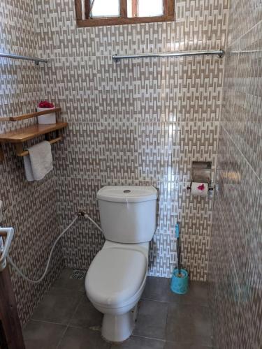 a bathroom with a toilet in a tiled wall at Kua Garden Bungalow in Utende