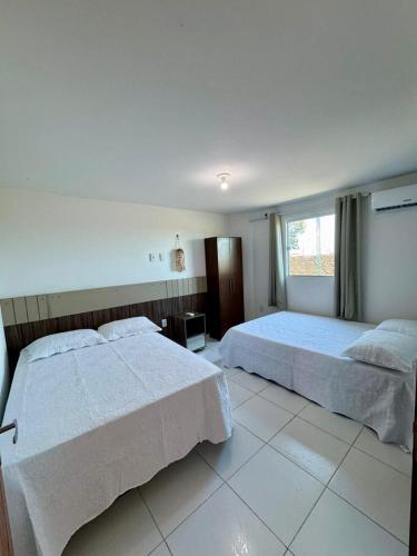 ein Schlafzimmer mit zwei Betten und einem Fenster in der Unterkunft Flats Varandas Praia Bela - Apto 103 in Pitimbu