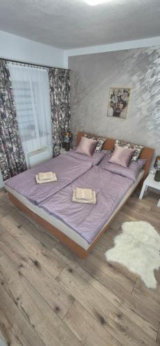 a bedroom with a purple bed with two towels on it at Krkonošský apartmán DELUXE in Poniklá