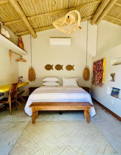 a bedroom with a large bed and a table at Casa Preguiça Corumbau in Corumbau
