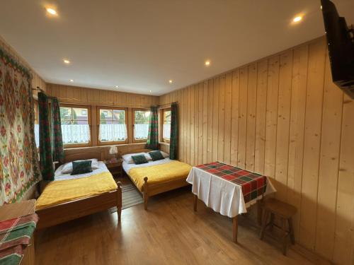 two beds in a room with wooden walls at Zakopane - Króle 16 in Zakopane