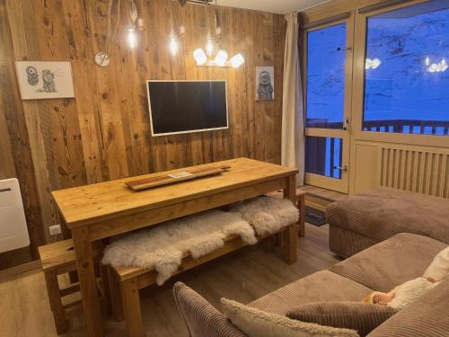 Una sala de estar con una mesa y un televisor. en Le Cocon, en La Mongie