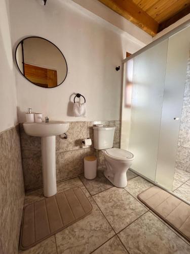 a bathroom with a toilet and a sink and a mirror at Amambay in Puerto Bossetti