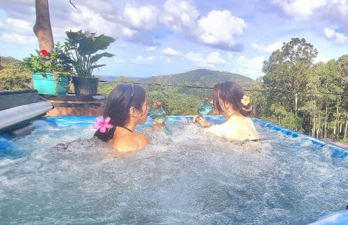 two girls are sitting in a swimming pool at The House of the Rising Sun & Hot Spa in Gold Coast