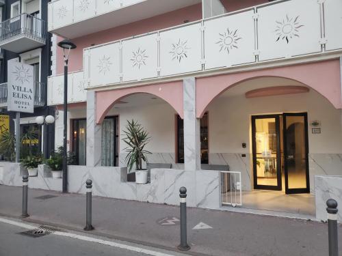 un edificio rosa e bianco su una strada cittadina di HOTEL VILLA ELISA a Rimini