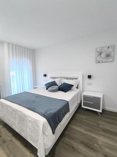 a white bedroom with a large bed with blue pillows at Casa de Campelo in Vila Nova de Cerveira