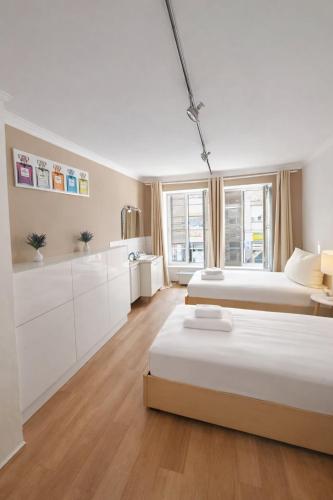 a white bedroom with two beds and a kitchen at Munich Premium Guesthouse in Munich