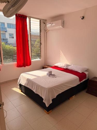 a bedroom with a bed with red curtains and a window at Hotel Atalayas in Yopal