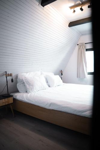 a bedroom with a bed with white sheets and a window at The Nest - Sauna and Hot Tub in Rynoltice