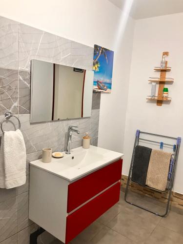a bathroom with a red and white sink and a mirror at Tilys house in Capesterre-Belle-Eau