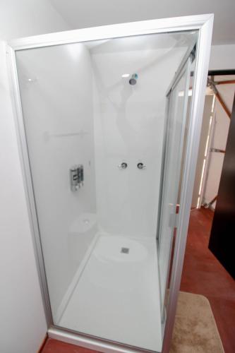 a glass shower door in a white room at Aldea Hualtepec Glamping in Huichapan