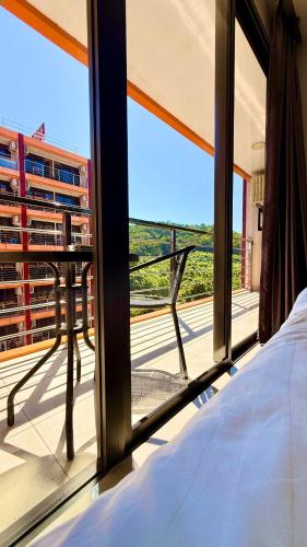 een slaapkamer met een bed en uitzicht op een balkon bij Bright Sun Apartment with Pools in Rawai Beach