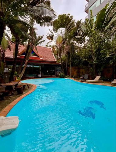 een groot blauw zwembad met palmbomen en een gebouw bij Bright Sun Apartment with Pools in Rawai Beach