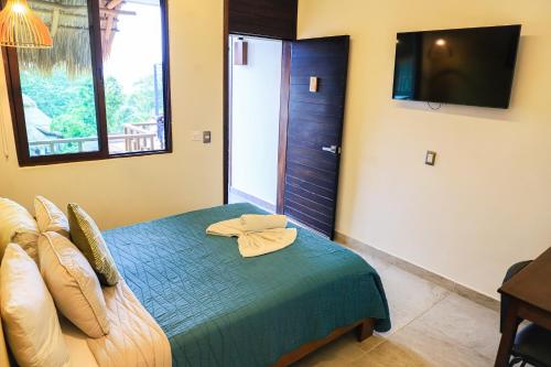 een slaapkamer met een bed en een televisie aan de muur bij Hotel Diosa del Agua Bacalar in Bacalar