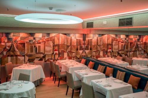 a restaurant with white tables and chairs and a wall at Hotel Opera in Madrid
