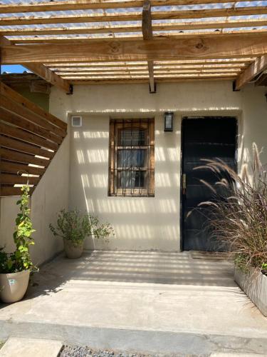 ein Haus mit einer schwarzen Tür und einem Holzdach in der Unterkunft La brisa in San Antonio de Areco