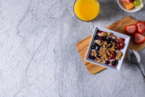 a bowl of cereal and fruit with a glass of orange juice at Hyatt House Royal Oak / Birmingham in Royal Oak