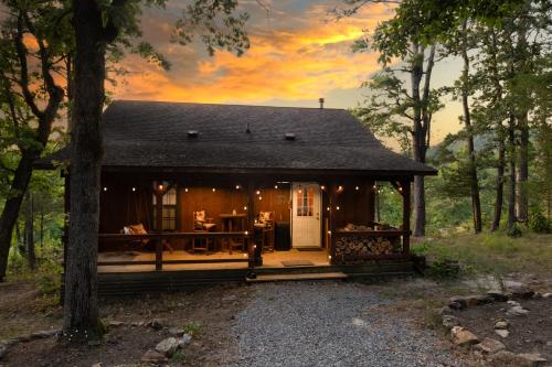 een blokhut in het bos met een zonsondergang bij Cliffside Cabin at Piney Falls - with Creek Access 