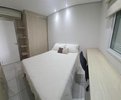 a small bedroom with a white bed and a desk at Apartamento Moderno 1 Quarto em Santos, Próximo à Praia e Comércio in Santos