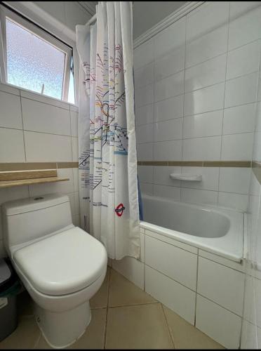 a white bathroom with a toilet and a bath tub at Departamento Luciana in Coquimbo