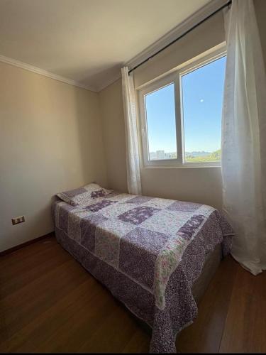 a bedroom with a bed and a large window at Departamento Luciana in Coquimbo