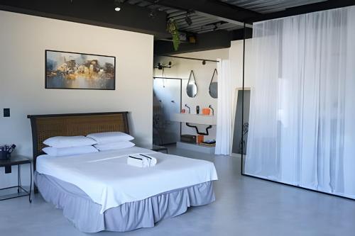 a bedroom with a large bed with white sheets at Casa Rústica - Próx à Praia in Saquarema
