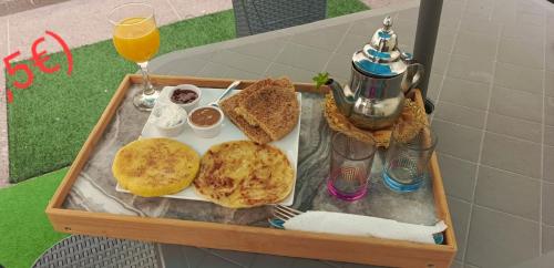 a tray of food with toast and bread and orange juice at Élégant Appartement près grand bazar "Souk elhad" in Agadir