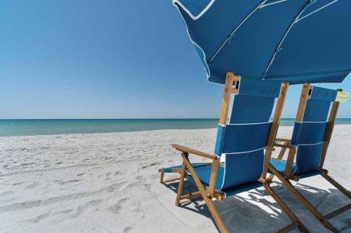 a blue chair and an umbrella on the beach at Waterfront Summer Vacay Free Private Beach Chairs & Umbrella Sleeps 5 in Destin
