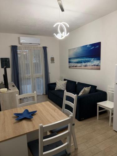 een woonkamer met een blauwe bank en een tafel bij Appartamento Sardinia Escape in residence - Palau in Palau