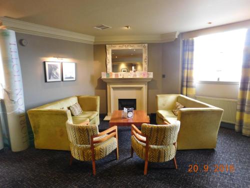 a living room with couches and a table and a fireplace at Horizon Hotel in Ayr